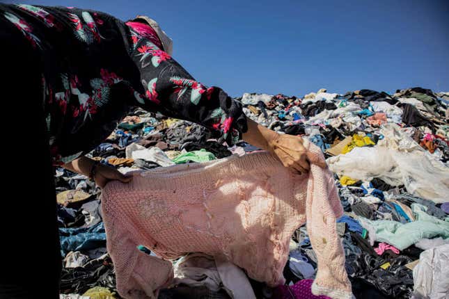 Una persona busca ropa en un montón de prendas desechadas en el desierto de Atacama