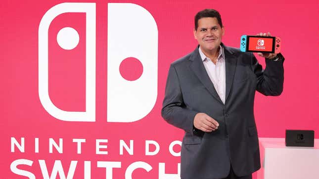 Former Nintendo of America president Reggie Fils-Aimé presents a Nintendo Switch on stage at an event. 