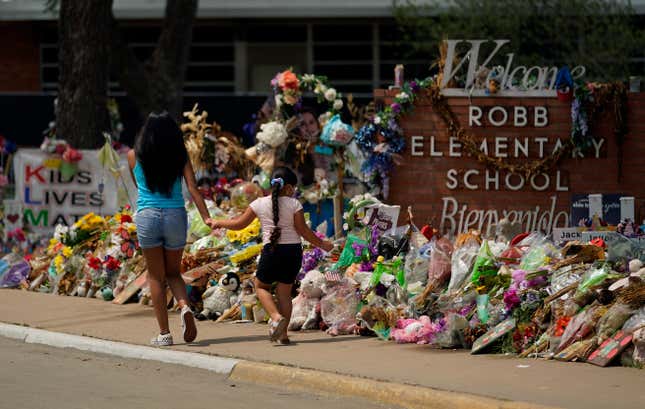 Visitors walk past a makeshift memorial honoring those recently killed at Robb Elementary School, Tuesday, July 12, 2022, in Uvalde, Texas. A Texas lawmaker says surveillance video from the school hallway where police waited as a gunman opened fire in a fourth-grade classroom will be shown this weekend to residents of Uvalde.