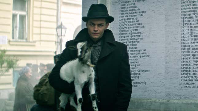A man in a hat holds a small goat