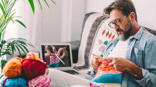 man watching a knitting tutorial on his computer, teaching himself to knit