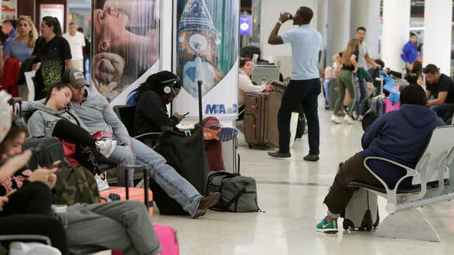 Travelers wait near a closed down terminal at the Miami International Airport on Saturday, Jan. 12, 2019, in Miami. The partial government shutdown is starting to strain the national aviation system, with unpaid security screeners staying home, air-traffic controllers suing the government and safety inspectors off the job. (AP Photo/Brynn Anderson)