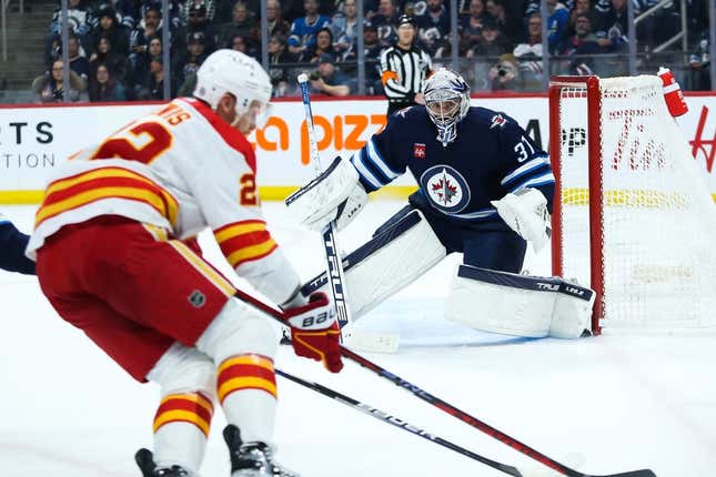 Apr 5, 2023; Winnipeg, Manitoba, CAN;  Winnipeg Jets goalie Connor Hellebuyck (37) watches Calgary Flames forward Trevor Lewis (22) during the first period at Canada Life Centre.