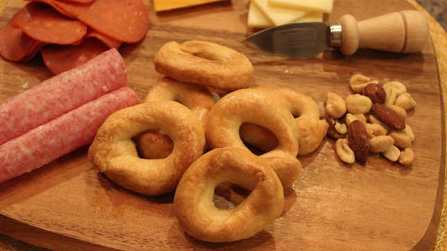 Homemade taralli on wooden board with meats, cheeses, and nuts