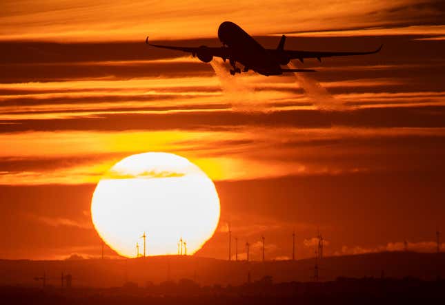 A plane takes off in front of the setting sun at Frankfurt Airport.