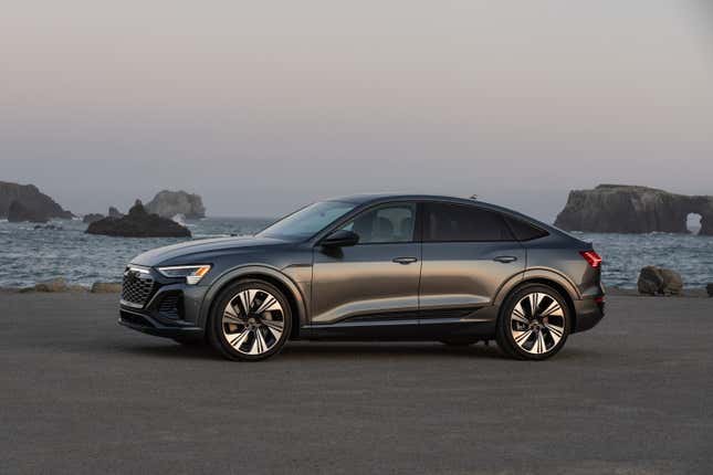 A gray 2024 Audi Q8 E-Tron Sportback is parked in front of the ocean, side view.