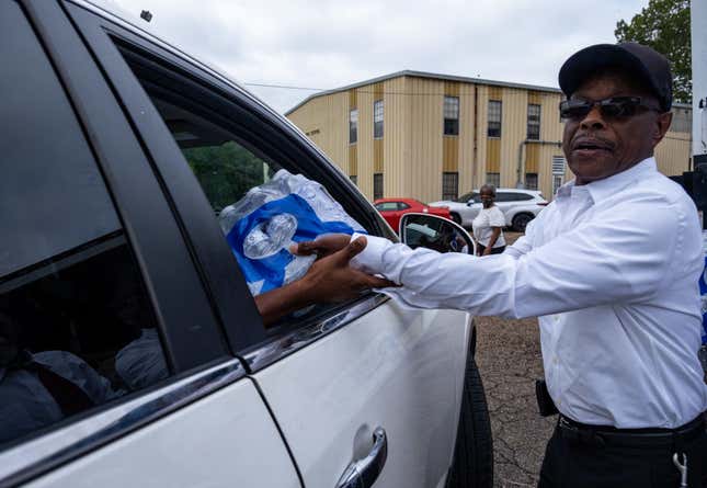 A member of Progressive Morningstar Baptist Church hands out cases of water after a Sunday morning service in Jackson, Mississippi, on September 4, 2022. - The church has reached out to various churches from across the state of Mississippi to help supply the church with bottled water to pass out to its congregation and the community as residents in Jackson continue to endure water setbacks. The city of Jackson, where 80 percent of the population is Black and poverty is rife, has experienced water crises for years. But this one is particularly severe, with many residents lacking clean running water for nearly a week.