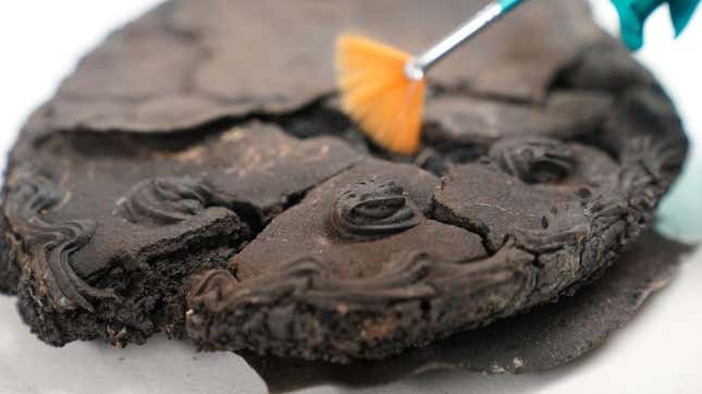 Forensic brush being applied to charred, flattened cake