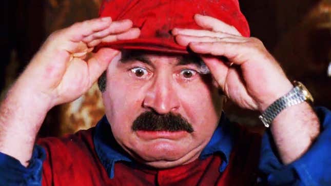 Bob Hoskins in the Super Mario Bros. movie is grabbing his red hat and looking despairing.
