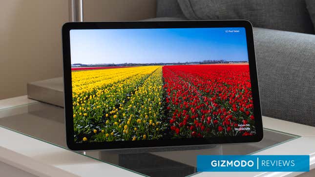 The Google Pixel Slate sitting on a side table next to a couch, with a field of colorful flowers on its screen.