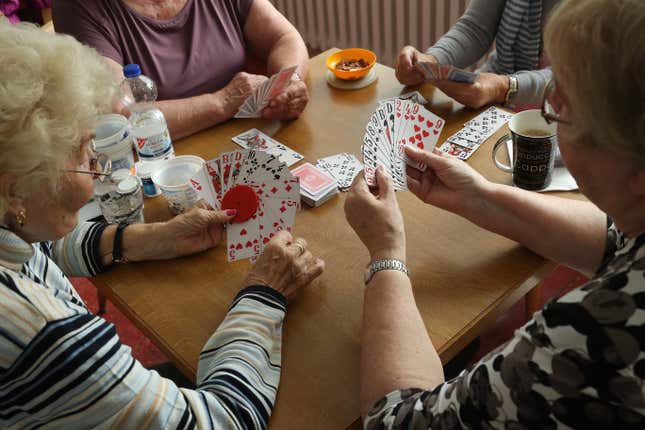 Elderly women play a card game of rummy.