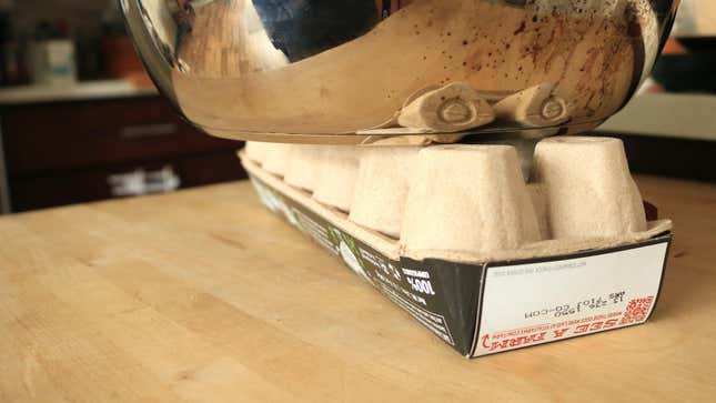 A heavy pot sits on top of an overturned egg crate.