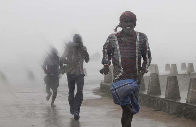 People run for shelter as heavy rain and wind gusts rip through the Bay of Bengal coast at Gopalpur, Orissa.