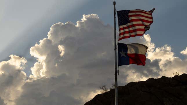 A photo of the Texas and American flags flying in the wind. 