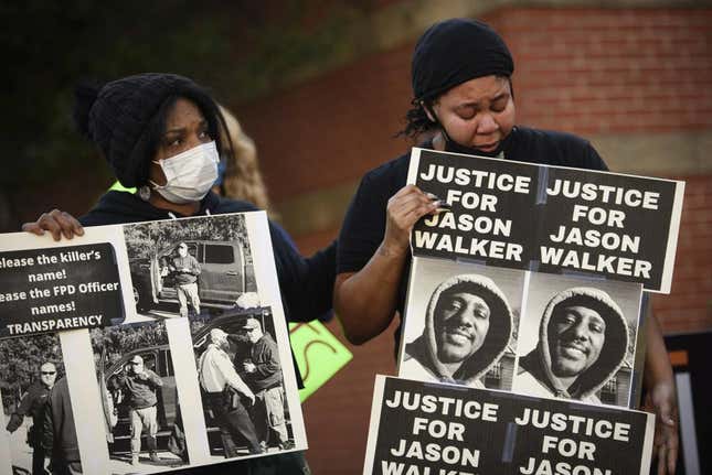 Pandora Harrington, right, cries as she holds a sign with an image of Jason Walker during a demonstration in front of the Fayetteville Police Department, Jan. 9, 2022, in Fayetteville, N.C. An autopsy released Thursday, March 24, 2022, by North Carolina’s Office of the Chief Medical Examiner said that 37-year-old pedestrian Jason Walker had wounds to his head, chest, back and thigh in the Jan. 8 shooting. The deputy has said he was defending himself after Walker jumped on the hood of his truck. The shooting prompted protests by demonstrators who questioned authorities’ account of what happened. 
