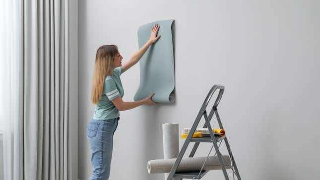 Woman hanging wallpaper 