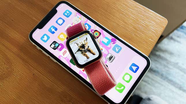 An Apple Watch with watchOS 8's Portrait watch face near an iPhone 11