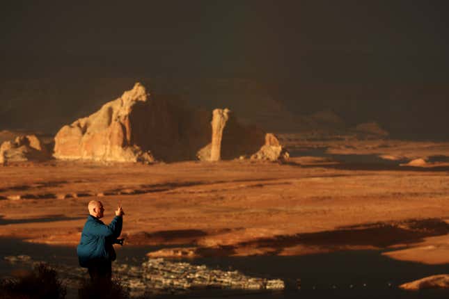 A park visitor takes a picture of Lake Powell at sunset.