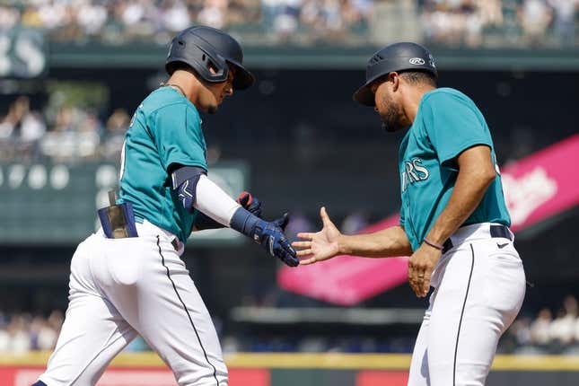 Aug 28, 2023; Seattle, Washington, USA; Seattle Mariners second baseman Josh Rojas (4, left) shakes hands with first base coach Kristopher Negr  n (45) after hitting a solo-home run against the Kansas City Royals during the third inning at T-Mobile Park.