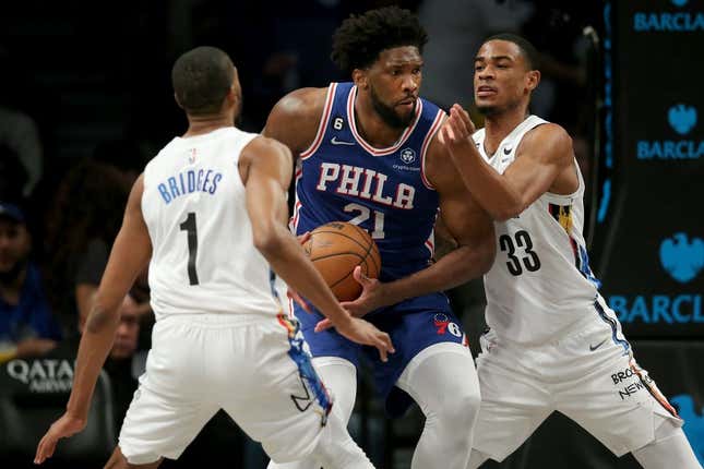 Feb 11, 2023; Brooklyn, New York, USA; Philadelphia 76ers center Joel Embiid (21) drives to the basket against Brooklyn Nets forward Mikal Bridges (1) and center Nic Claxton (33) during the third quarter at Barclays Center.