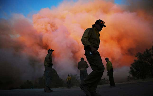 U.S. Forest firefighters stand watching a wildfire called the Oak Fire burn east of Midpines in Mariposa County, Calif., Friday, July 22, 2022