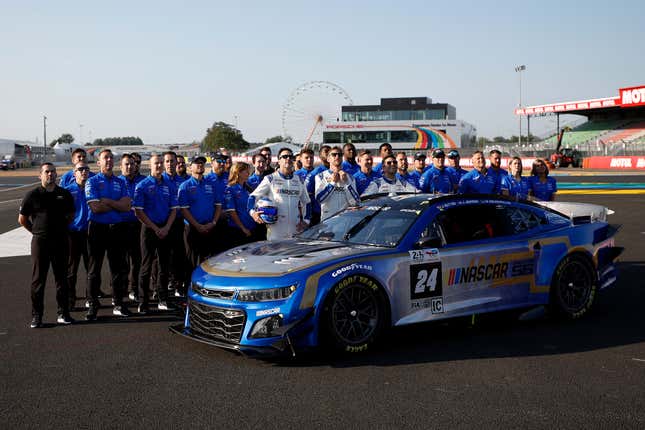 Jimmie Johnson, Jenson Button y Mike Rockenfeller, pilotos del Chevrolet ZL1 de próxima generación n.º 24 de NASCAR, posan para una foto con todo su equipo antes del 100.° aniversario de las 24 Horas de Le Mans.