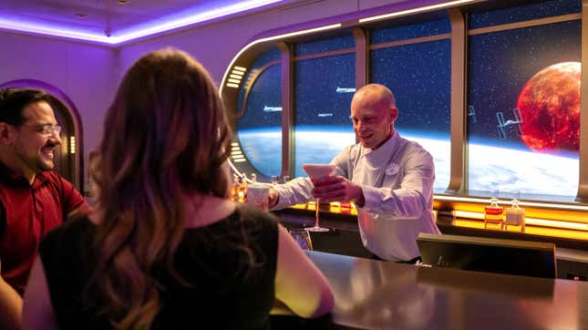 two people get handed drinks from a bartender at the immersive star wars bar on the disney wish