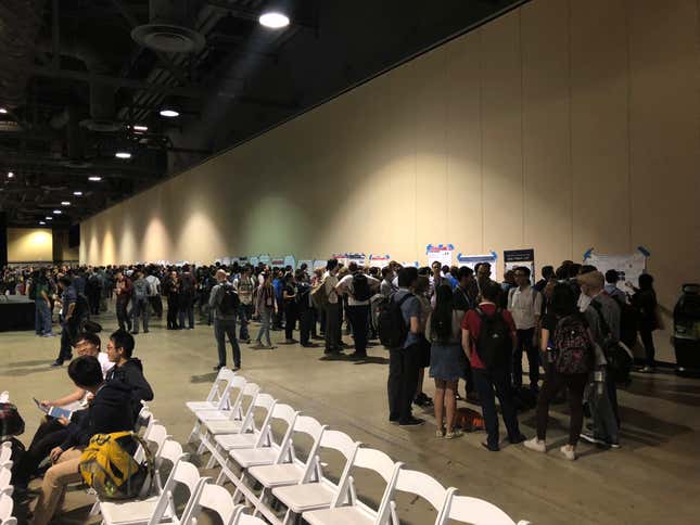 Researchers crowd around posters taped to the walls of the convention center.