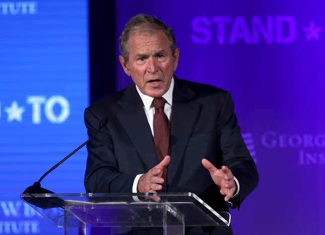 George W. Bush stands at a lectern with his hands in front of him