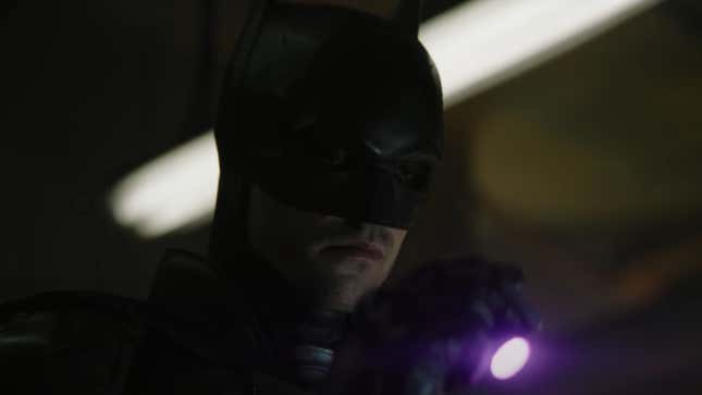 The Batman looks down at something exposed by his ultraviolet flashlight.