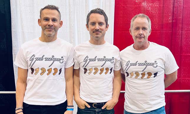 Dominic Monaghan, Elijah Wood, and Billy Boyd pose in shirts that read “You Are All Welcome Here.”