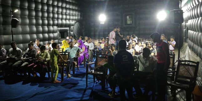 The audience waits for the movie to begin inside the theatre.