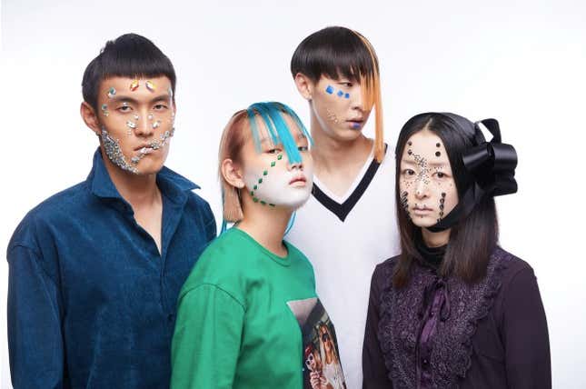 A group of people wearing makeup with jewels and shapes stuck to your face.
