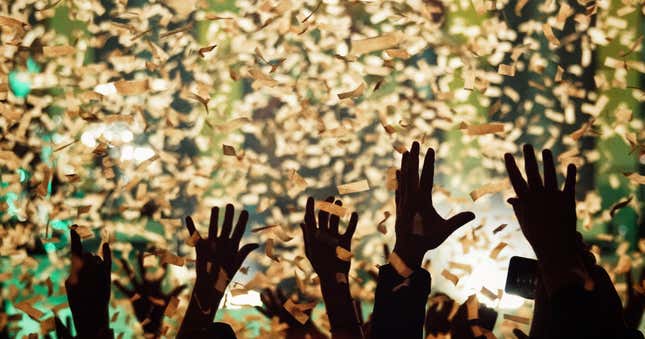hands raised in the air in celebration amid a swirl of confetti