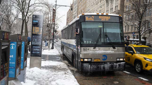 A photo of a bus driving on a snowy street in New York. 
