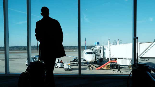 Person stands at airport gate looking out window at plane