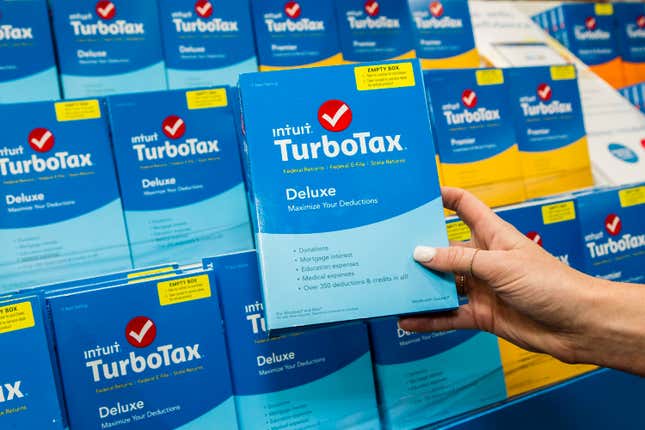 A hand holds up a box containing TurboTax deluxe software.