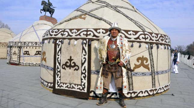 a man in ethnic costume in front of a yurt
