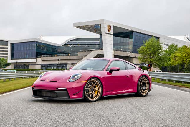 A ruby ​​Porsche 911 GT3 equipped with the Manthey Performance Kit is parked in front of Porsche's headquarters, seen from the front area.