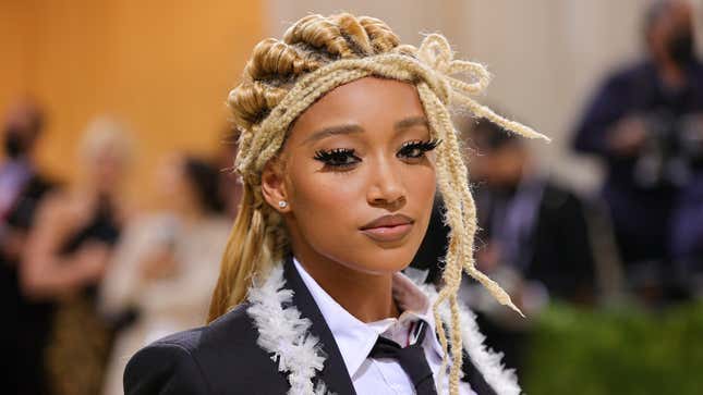 Amandla Stenberg with blonde, braided hair and a black jacket at the 2021 Met Gala.