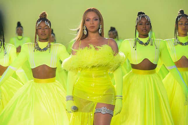 Beyonce and her back up dancers are all dressed in yellow and standing in a line.