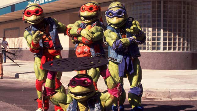 A photo shows the TMNT gang standing together in a the street as one lifts up a manhole cover.