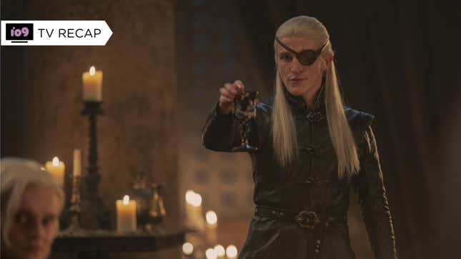 The one-eyed Aemond Targaryen raises a goblet and toasts his nephews in candelight.