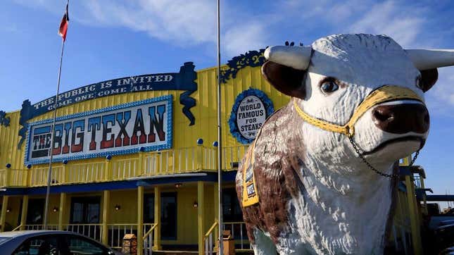 front of the big texan restaurant with giant cute cow statue