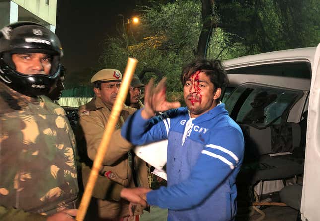 The police detain an injured student outside Jamia Millia Islamia.