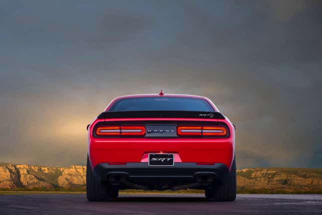 A red 2023 Dodge SRT Challenger Hellcat is parked with storm clouds around it.