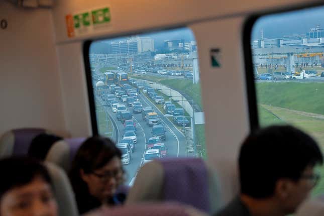 Travelers sit on the Airport Express train as vehicles are clogged with heavy traffic heading to the airport during a protest at the Hong Kong International Airport, Aug. 12, 2019.