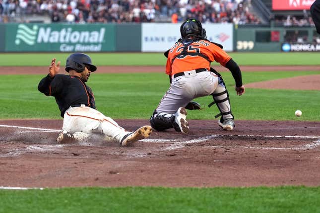 Jun 3, 2023; San Francisco, California, USA; San Francisco Giants first baseman LaMonte Wade Jr. (31) slides into home plate to score a run as Baltimore Orioles catcher Adley Rutschman (35) waits for a throw during the third inning at Oracle Park.