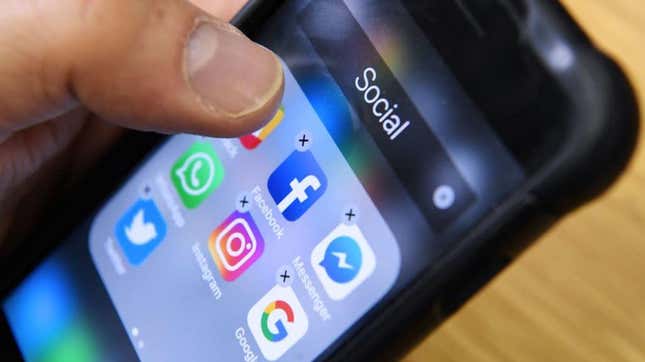 Hand holding phone with social media apps pulled up on screen