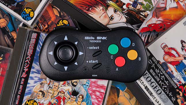 The 8BitDo NEOGEO CD Wireless Controller sitting on top of a pile of NEOGEO CD games in their jewel cases.